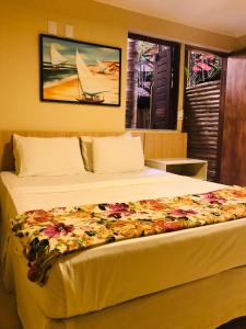 a hotel room with two beds and a painting on the wall at Hotel Pousada Latitude in Canoa Quebrada