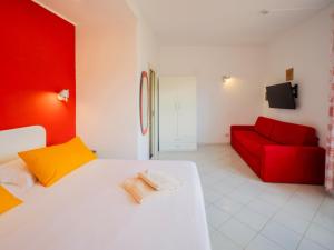 a bedroom with a white bed and a red couch at Hotel Cristina in Sorrento