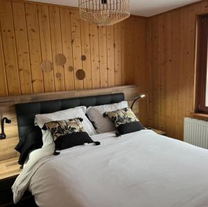 a bedroom with a large white bed with wooden walls at Les gîtes de la Serva in Belmont