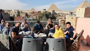een groep mensen aan tafels op een dak met piramides bij Gohar Guest House in Caïro