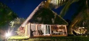 une petite cabane avec un toit de chaume et des chaises dans l'établissement KINTANA LODGE, sur l'île aux Nattes