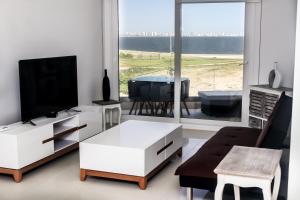 sala de estar con TV, sofá y mesa en Azure Towers, en Punta del Este