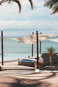 a bed with a white umbrella on a beach at Orchid House Baja in La Paz