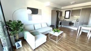 a living room with a white couch and a kitchen at Dúplex con terraza by Prestigi in Terrassa