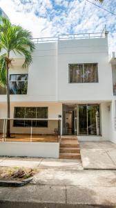 a white house with a palm tree in front of it at Casa en cartagena con jacuzzi in Cartagena de Indias