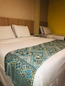 two beds in a hotel room with a blanket on the bed at Hotel Pousada Latitude in Canoa Quebrada