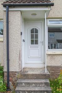 a white door on a house with stairs at Greenside Getaway in Newarthill
