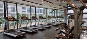 a gym with a row of treadmills and ellipticals at The Robertson Kuala Lumpur by PremierHome 5-6pax in Kuala Lumpur