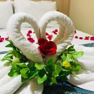 Dos toallas con forma de corazón en una cama con una rosa en Hotel Pousada Latitude, en Canoa Quebrada