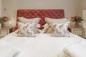 a white bed with a red headboard and white pillows at Clarence House: 4BD Georgian Townhouse in Cheltenham