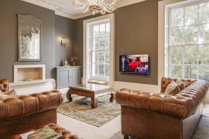 a living room with a couch and a tv at Clarence House: 4BD Georgian Townhouse in Cheltenham