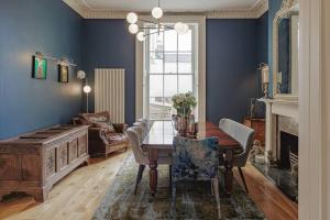 a dining room with a table and a living room with blue walls at Clarence House: 4BD Georgian Townhouse in Cheltenham