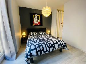 a bedroom with a black and white bed and a chandelier at Le François Fabié T2 Hyper-Centre Rodez in Rodez