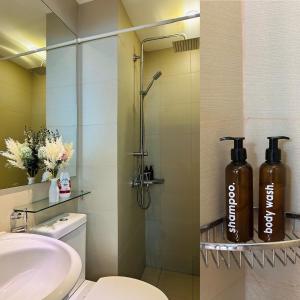 a bathroom with a sink and a shower with two large bottles at Azure Staycation Near the Airport in Manila