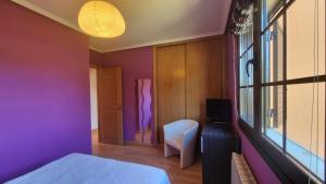 a bedroom with purple walls and a bed and a window at Apartamento La Ventana del Cuera in Llanes