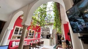 un restaurante con una pared roja, mesas y sillas en El Rey Moro Hotel Boutique, en Sevilla