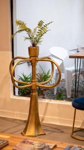 a potted plant on a gold stand in front of a table at Hostal Casa Mosaiko Patio Bonito Poblado in Medellín