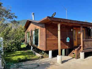 eine kleine Holzhütte mit einer Veranda und einer Tür in der Unterkunft CASA EN COBQUECURA SE ARRIENDA in Cobquecura