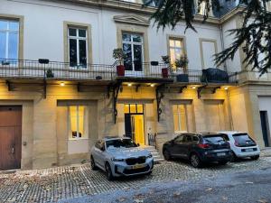 dos coches estacionados frente a un edificio en La cour de la Trésorerie en Metz