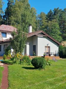 una pequeña casa blanca con un patio de césped en Plieņciems Urgas Mazais numurs, en Plieņciems