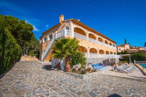 un gran edificio con sillas y una palmera en Villa Zelda - PlusHolidays, en Calpe