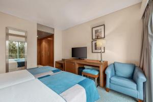 a hotel room with a bed and a chair and a television at Hotel Do Caracol in Angra do Heroísmo
