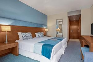 a hotel room with a large bed and a television at Hotel Do Caracol in Angra do Heroísmo