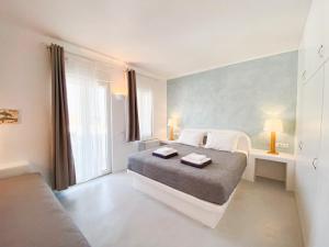 a white bedroom with a bed and a window at Villas Scirocco in Fira