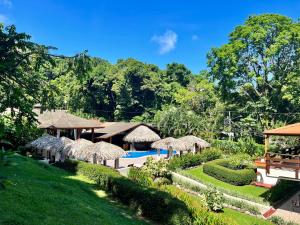a resort with a swimming pool and straw umbrellas at Hotel Playa Espadilla & Gardens in Manuel Antonio