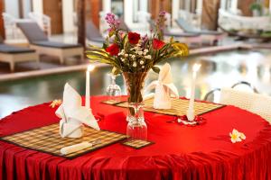una mesa roja con un jarrón de flores y velas en North Wing Canggu Resort en Dalung