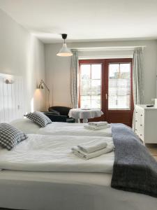 Una gran cama blanca con toallas encima. en Landhaus Nordstern Hotel garni, en Utersum