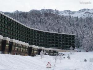 un gran edificio en la nieve con montañas en el fondo en Studio Villard-de-Lans, 1 pièce, 4 personnes - FR-1-515-183, en Villard-de-Lans
