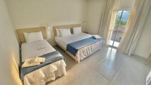 um quarto de hotel com duas camas e uma janela em Pousada Aquino Mar em Paraty
