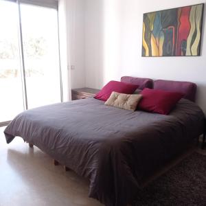Bel appartement à skhirat plage et à 20 mn de Rabat في الصخيرات‎: غرفة نوم بسرير كبير ومخدات حمراء