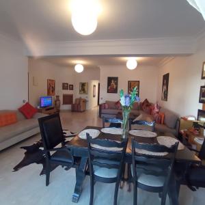 Bel appartement à skhirat plage et à 20 mn de Rabat في الصخيرات‎: غرفة معيشة مع طاولة وكراسي وأريكة
