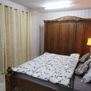 1 cama con cabecero de madera en un dormitorio en العين الهيلي مصباح ب 7 en Al Ain