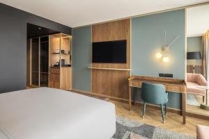 ポルトにあるRenaissance Porto Lapa Hotelのベッド、デスク、テレビが備わるホテルルームです。