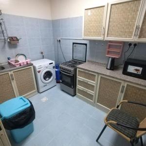 una piccola cucina con piano cottura e lavatrice di العين الهيلي مصباح ب 7 a Al Ain