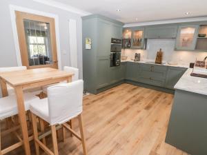 a kitchen with green cabinets and a wooden table at Golygfa Bryn in Porth