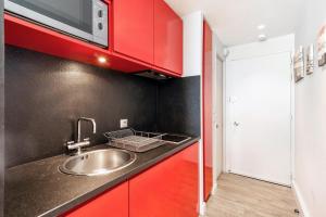 Una cocina con fregadero y armarios rojos. en Biarritz - Residence Victoria surf - Face océan, en Biarritz 5 fotos más