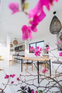 ein Esszimmer mit einem Tisch und rosa Blumen in der Unterkunft APS House Pererenan in Canggu