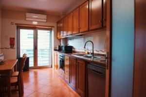 a kitchen with wooden cabinets and a sink and a table at Celorico Village AP in Celorico de Basto