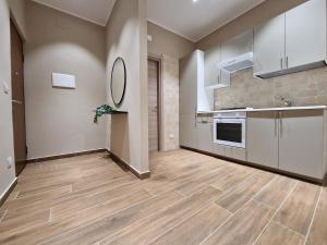 uma grande cozinha com pisos em madeira e armários brancos em Piccole Donne em Nápoles