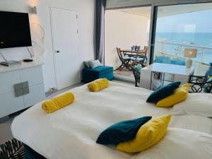een groot wit bed met gele en blauwe kussens erop bij Biarritz - Le Miramar - Studio face ocean in Biarritz