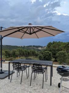 una mesa y sillas bajo una sombrilla grande en Modern and spacious Cork House with private valley view, en Caldas da Rainha