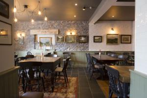 a restaurant with tables and chairs and a stone wall at Bridge End Hotel in Llangollen