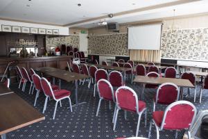 una sala de conferencias con mesas, sillas y una pantalla en Bridge End Hotel, en Llangollen