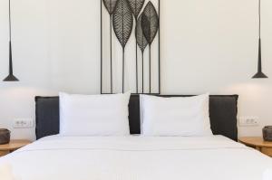 una camera da letto con un grande letto con lenzuola e cuscini bianchi di Nostos Apartments Kamari a Kamari