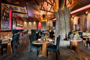 un restaurante con mesas, sillas y un árbol en El Dorado Seaside Palms, Catamarán, Cenote & More Inclusive, en Akumal