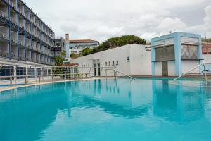 une grande piscine d'eau bleue devant un bâtiment dans l'établissement Hotel Do Caracol, à Angra do Heroísmo